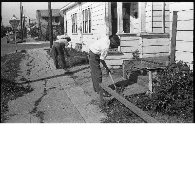 Two men working with shovels in yard