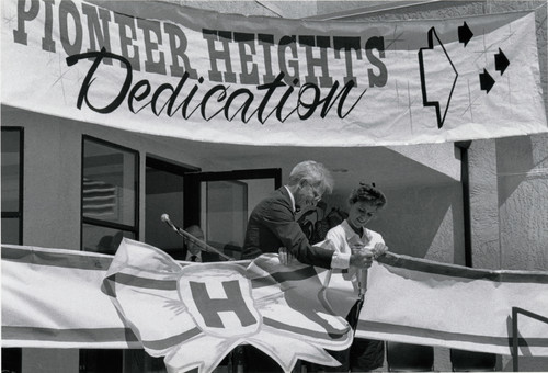 Photograph of the Pioneer Heights Dedication Ceremony ribbon cutting with President Ellis E. McCune and unknown girl (student)