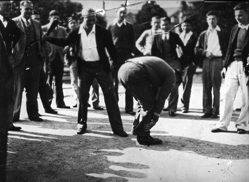 [A man preparing to strike another man while a crowd watches]