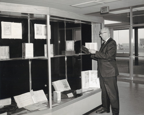 A photograph of Library Director Floyd Erickson handling items from the DeBellis Collection on loan from San Francisco State University