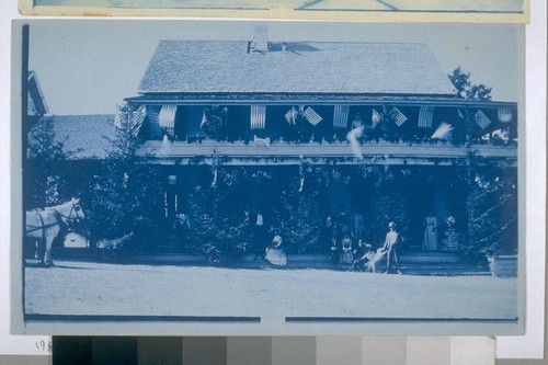 [Large house with many American flags, and a group of people in front]