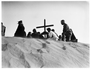 People seated near a cross during a funeral