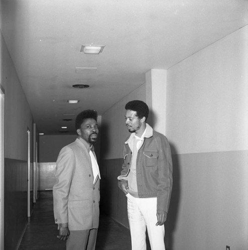 Roland Bynum and an unidentified man talking in a hallway, Los Angeles, 1969