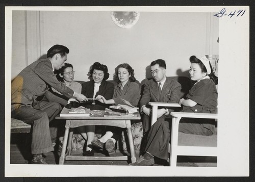 Joe Oyama is doing a card trick in the living room of the apartment which he and Mrs. Oyama, formerly