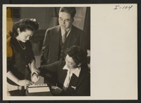 Misako Tomita of the Relocation Office is helping Mrs. Thomas T. Sashihara have her finger prints taken for the file