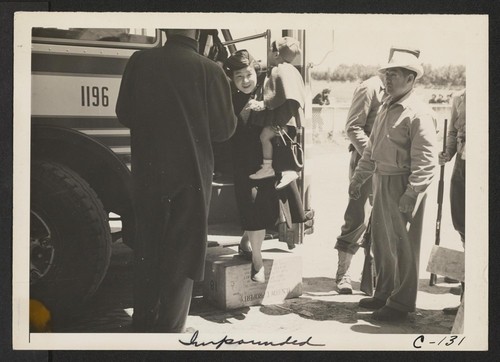 Arriving at the assembly center, the man at the right is a volunteer Japanese worker assisting at the induction. Photographer: Lange, Dorothea San Bruno, California