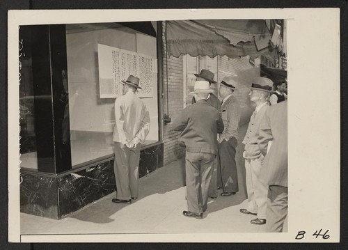 Los Angeles, Calif.--Reading bulletins in Japanese language in Little Tokyo when residents of Japanese ancestry were instructed to evacuate. They will be assigned to War Relocation Authority centers for the duration. Photographer: Albers, Clem Los Angeles, California