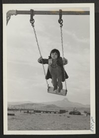 One of the young Heart Mountain school children is enjoying a swing on the center's play ground. Photographer: Iwasaki, Hikaru Heart Mountain, Wyoming