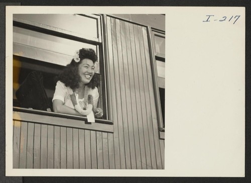 Closing of the Jerome Center, Denson, Arkansas. An attractive Miss, aboard the train for Gila River, smiles as she calls to her friends who assembled at the train to say Aloha. Photographer: Iwasaki, Hikaru Denson, Arkansas