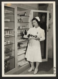 Miss Ruth Tanaka, a cadet nurse in the Seton Training School for Nurses, holds a tray of medicines in the