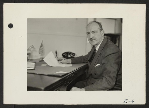 Charles F. Ernst, Project Director, at his desk in the Administration building at the Topaz Relocation Center. Photographer: Parker, Tom Topaz, Utah