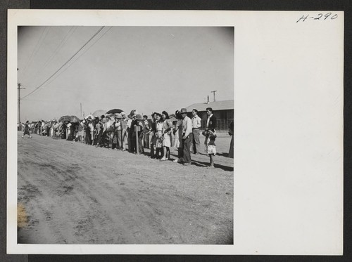 Topaz residents line the fence to watch bus loads of departing transferees pass by on their way to Delta, Utah, to entrain for Tule Lake. Photographer: Mace, Charles E. Topaz, Utah