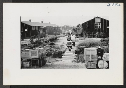 Segregees from a typical block bringing checkable baggages to the street where they received check stubs before the baggages are transported to the rail head by truck. Photographer: Lynn, Charles R. Denson, Arkansas