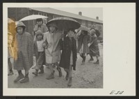 Grade school children leaving the school, at the Jerome Relocation Center. During the rainy season, in the heart of the Arkansas lowlands, the Jerome Center, whose residents are former Californians of Japanese ancestry, was one vast quagmire. Photographer: Parker, Tom Denson, Arkansas