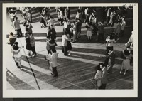Dancing is one of the chief forms of recreation at the Heart Mountain Relocation Center. This scene, in the high school gymnasium, shows the portion of the crowd at a school dance to which the public was invited. Photographer: Iwasaki, Hikaru Heart Mountain, Wyoming