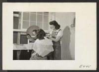 With makeshift equipment and arrangements, the cooperative beauty salon does a rushing business. Photographer: Parker, Tom Amache, Colorado