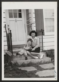 Joe Carl Thoman, Jr., grandson of Carl Sandburg, poet and biographer, plays with Sanao Imoto, Mr. Sandburg's secretary, at the entrance to the Thoman home adjoining the Sandburg goat farm. Joe Carl and Sanao are close friends and spend many happy hours together. Harbert, Michigan