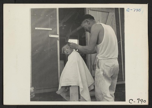 Manzanar, Calif.--Little evacuee of Japanese ancestry gets a haircut. Photographer: Lange, Dorothea Manzanar, California