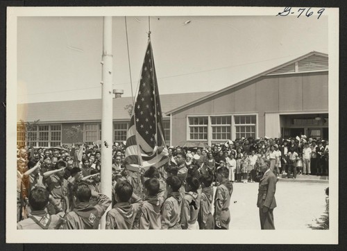 Amache Boy Scouts raising flag to half-mast at Memorial Service for first six Nisei soldiers from this Center killed in action in Italy. The service was held August 5, 1944, and attended by 1500 Amache residents. Photographer: McClelland, Joe Amache, Colorado