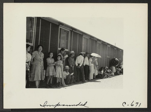 Part of a line waiting for lunch outside the mess hall at noon. Photographer: Lange, Dorothea Manzanar, California