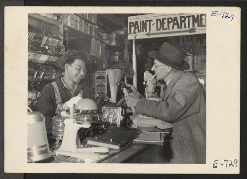 Joe Sitsuda, a former Los Angeles vegetable and fruit clerk who spent two months in a relocation center at Poston, Arizona, is selling a hammer to a customer in the Union Hardware Store in Denver, Colorado, where he is now employed. Photographer: Parker, Tom Denver, Colorado