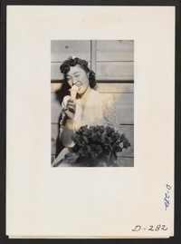 Labor day queen eats an ice cream cone and winks at the photographer at the celebration which was held after the coronation ceremony and was only part of the celebration at this relocation center. Photographer: Stewart, Francis Newell, California