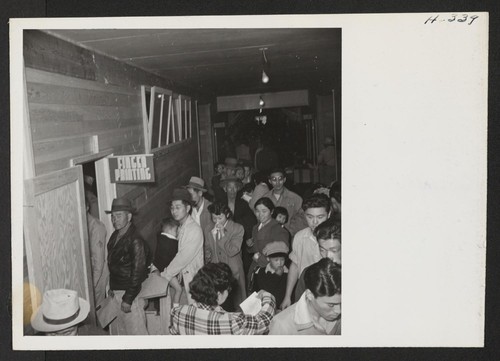 Tule Lake induction center. New arrivals from Topaz are shown waiting to have their identification pictures taken and finger prints made. Photographer: Mace, Charles E