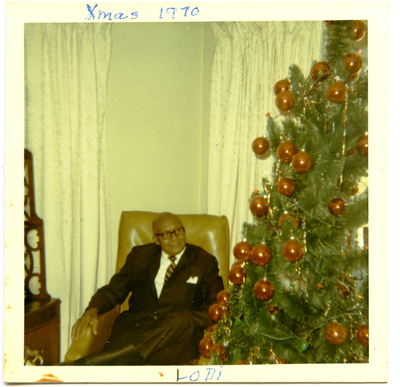 William Watts sitting in chair next to Christmas tree, Lodi, Texas