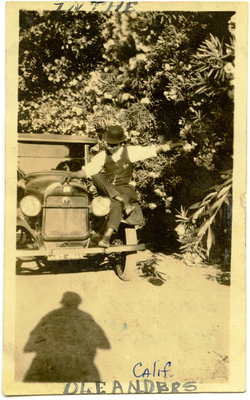 William Watts sitting on front fender of car