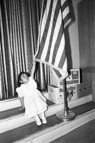 Girl sitting next to a flag at Beulah Payne Elementary School, Inglewood, California, 1983