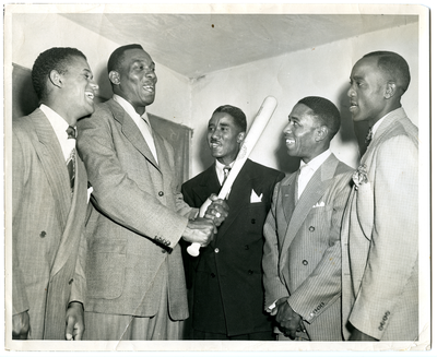 Four unidentified men in suits, one holding a bat