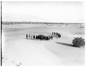 Group of people standing in a semi-circle in the desert for a funeral