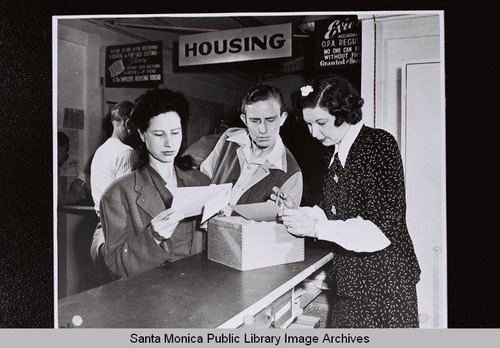 Housing Bureau clerk reviews cards of available housing with Douglas Aircraft Company employees during World War II