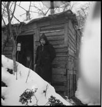[Misc.: woman at shack in snow]