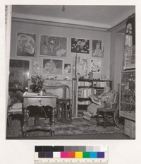 [Henri Matisse in his home, seated in a chair, looking at a book.]