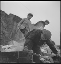 Cleaning attics [Men and boys going through piles of household things in the street]