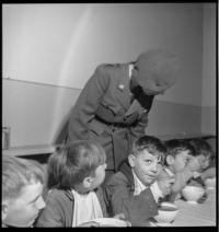 Cantine scolaire [School cafeteria. Women serving children eating at tables. Comite Americain de Secours Civil]