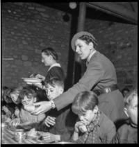 Cantine scolaire [School cafeteria. Women serving children eating at tables. Comite Americain de Secours Civil]