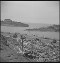 Cleaning attics [Men and boys going through piles of household things in the street]