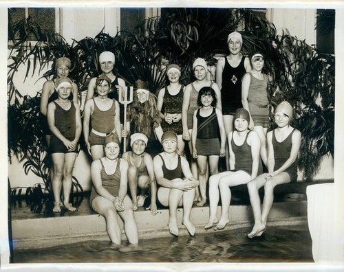 Swimmers posing at the edge of a pool during a water pageant