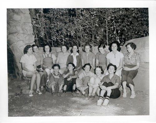 Group portrait of teenage girls outside by a large stone hearth