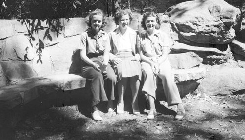 Three teenage girls sitting on a stone bench