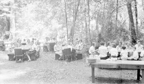 Large group of girls and women eating at picnic tables