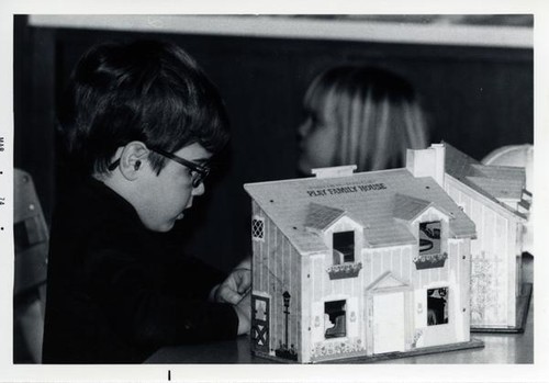 Little boy next to a doll house