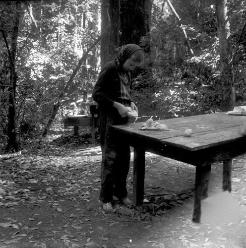 Girl making something with clay at a wood table outdoors