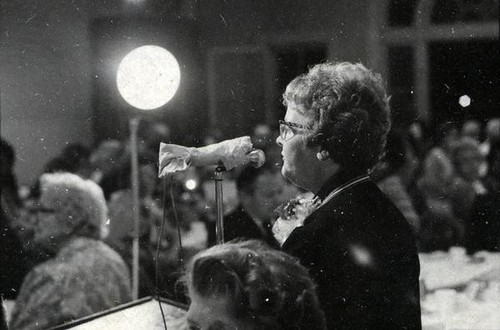 Mrs. Earl Dailey at a microphone