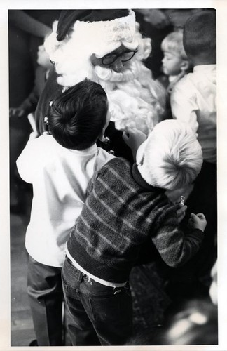 Two little boys standing next to Santa