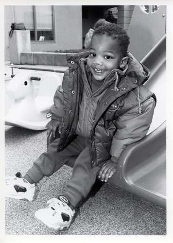 Young boy sitting at the bottom of a slide