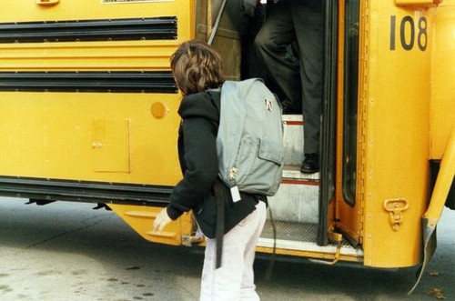 Child walking next to a school bus