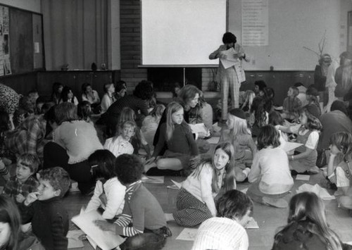 Group of children with papers sitting on the floor